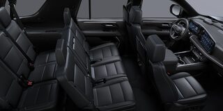 Vista completa del interior de la Chevrolet Suburban con tres filas de asientos en cuero negro y tablero digital