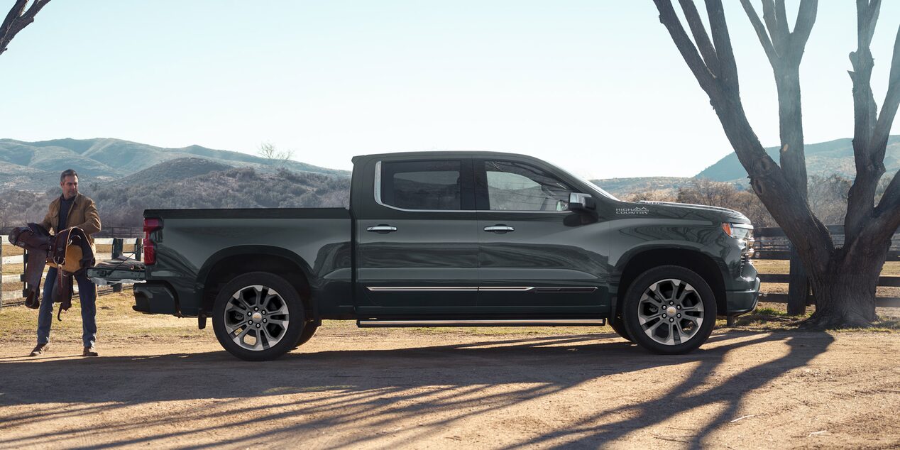 Vista lateral de la Chevrolet High Country con un hombre cargando la caja.