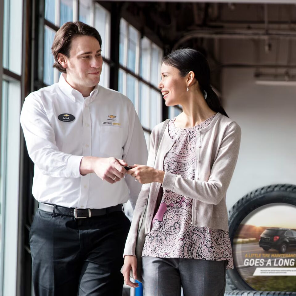 Imagen de un asesor de Chevrolet dándole la llave de un vehículo a una nueva clienta.