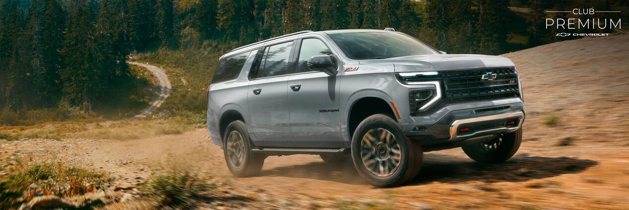 Chevrolet Suburban ascendiendo por un camino de piedra en la montaña, con pinos de fondo.
