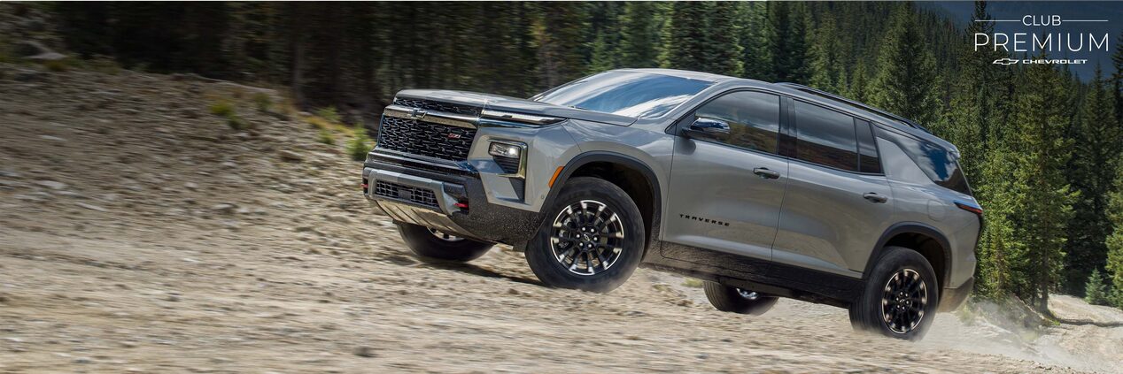 Chevrolet Traverse ascendiendo por una carretera de piedra en la montaña, con pinos de fondo.