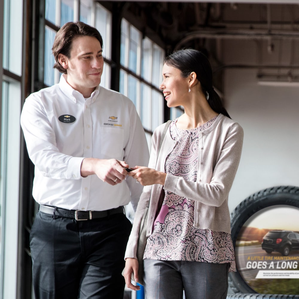 Ejecutivo de Chevrolet entregando las llaves a una clienta satisfecha en el concesionario