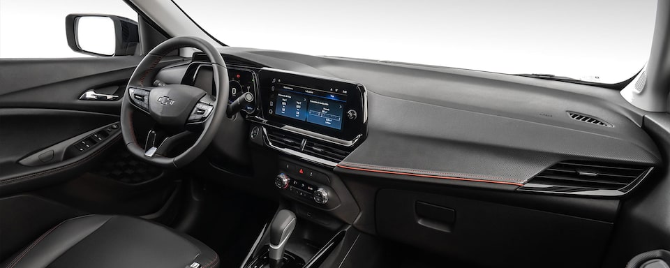 Vista interior y delantera de la Chevrolet Montana, mostrando volante, pantalla central y controles y guantera.