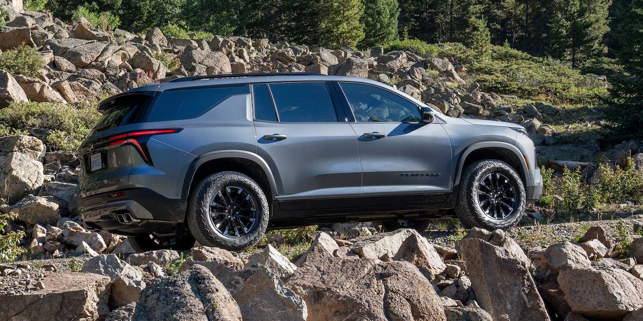 Vista lateral de Chevrolet Traverse cruzando un camino de piedras.